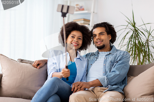 Image of happy couple with smartphone taking selfie at home