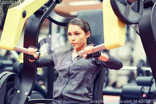 Image of woman flexing muscles on chest press gym machine 