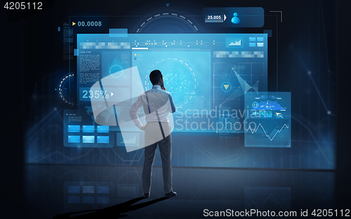 Image of businessman looking at virtual screens over dark