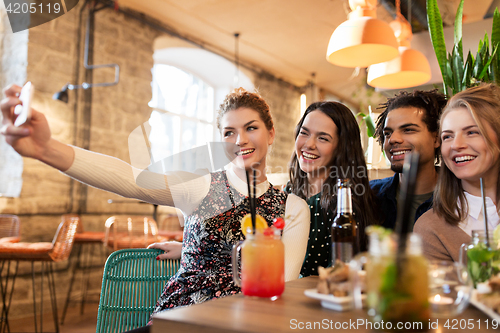 Image of friends taking selfie by smartphone at bar or cafe