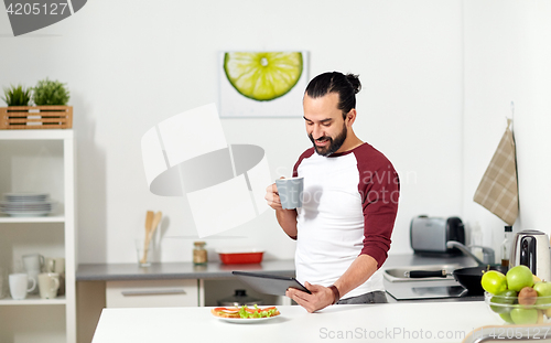 Image of man with tablet pc eating at home kitchen