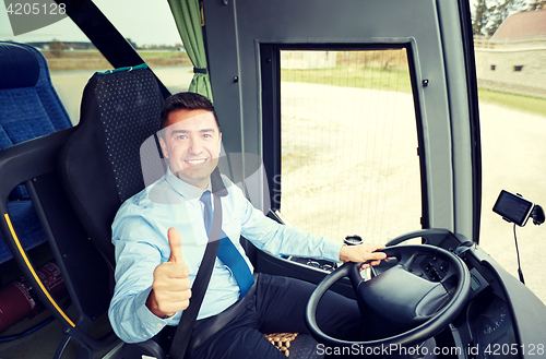 Image of happy driver driving bus and snowing thumbs up