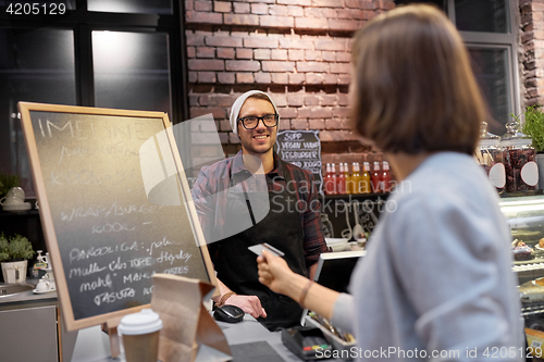 Image of barman and woman paying with credit card at cafe