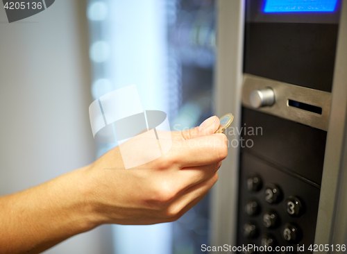 Image of hand inserting euro coin to vending machine