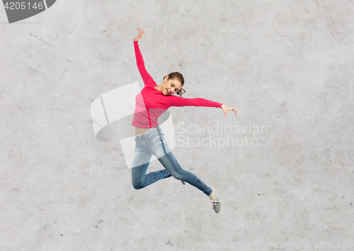 Image of happy young woman jumping in air or dancing