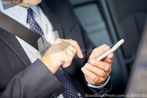 Image of senior businessman texting on smartphone in car