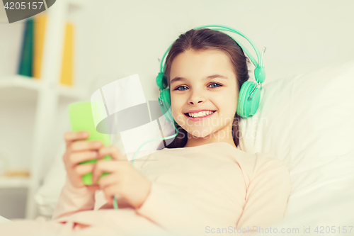 Image of happy girl lying in bed with smartphone at home