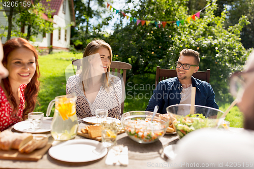 Image of happy friends having dinner at summer garden party