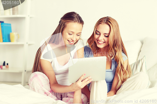 Image of happy friends or teen girls with tablet pc at home