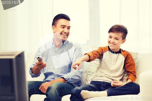 Image of smiling father and son watching tv at home