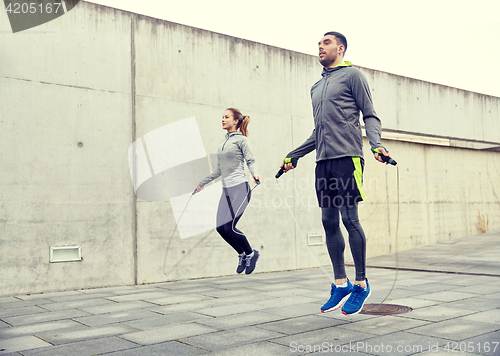 Image of man and woman exercising with jump-rope outdoors