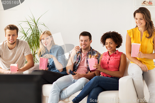 Image of happy friends with popcorn watching tv at home