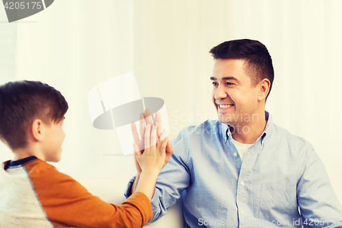 Image of happy father and son doing high five at home