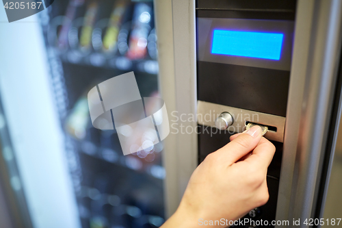 Image of hand inserting euro coin to vending machine slot