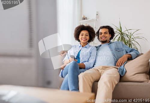 Image of smiling couple with remote watching tv at home