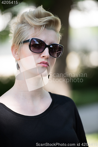 Image of young woman with short blond hair and sunglasses