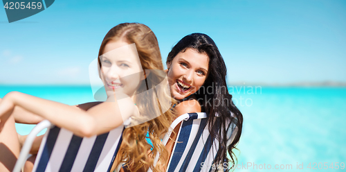 Image of happy women sunbathing in chairs over blue sea