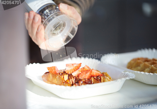 Image of close up of hand with spice mil spicing waffle