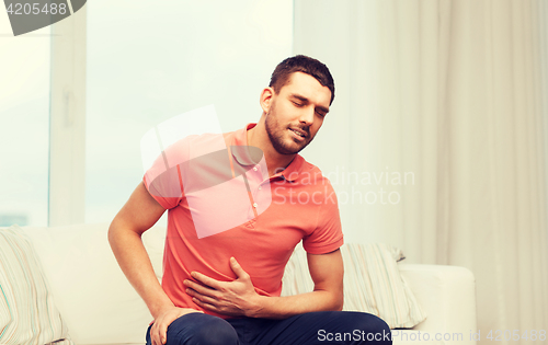 Image of unhappy man suffering from stomach ache at home