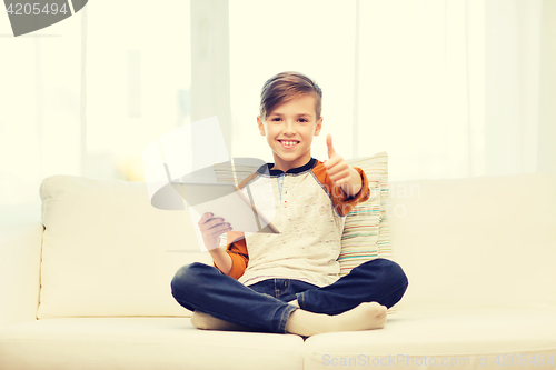 Image of smiling boy with tablet showing thumbs up at home