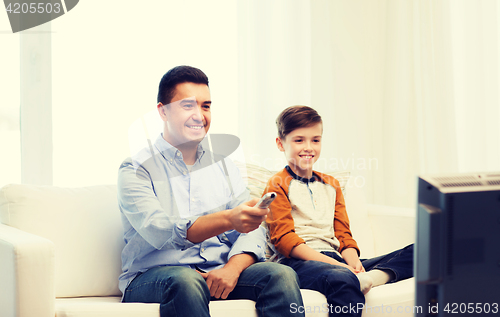 Image of smiling father and son watching tv at home