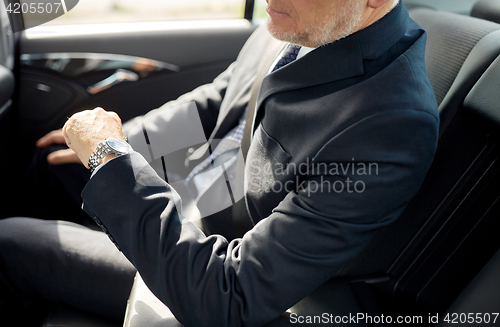 Image of senior businessman driving on car back seat