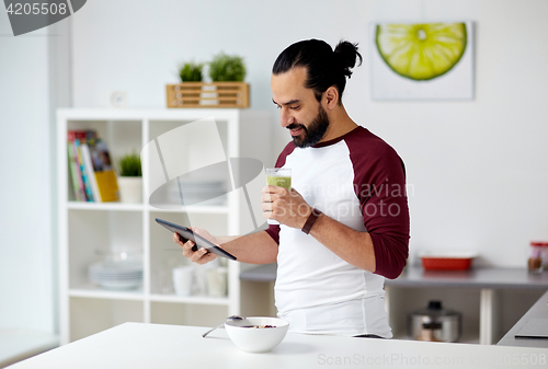 Image of man with tablet pc eating breakfast at home