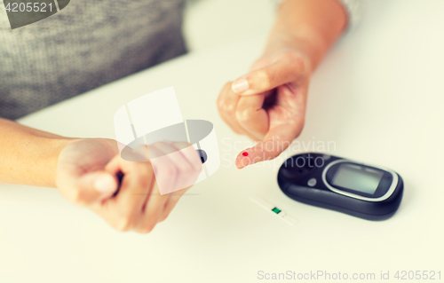 Image of close up of woman making blood test by glucometer