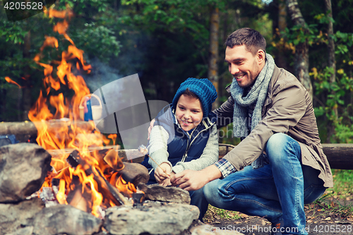 Image of father and son roasting marshmallow over campfire