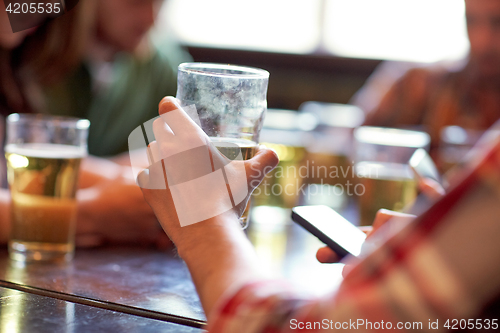 Image of man with beer and smartphones at bar or pub