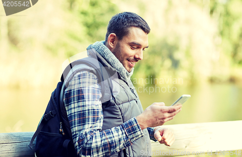 Image of happy man with backpack and smartphone outdoors