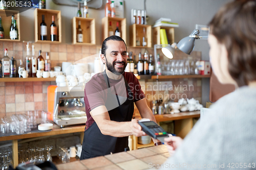 Image of man or waiter with card reader and customer at bar