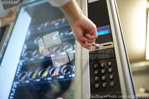 Image of hand pushing button on vending machine
