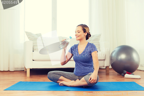 Image of happy woman with water bottle exercising at home
