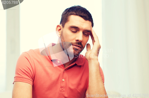 Image of unhappy man suffering from headache at home