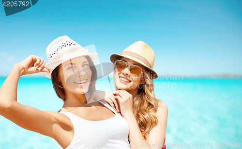 Image of happy young women in hats on summer beach
