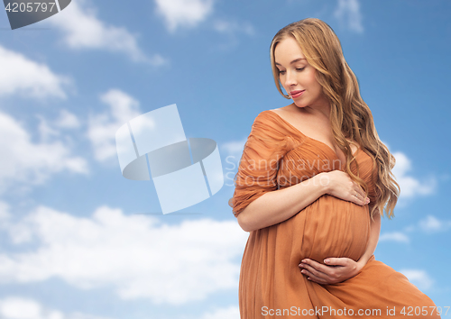 Image of happy pregnant woman touching her belly over sky