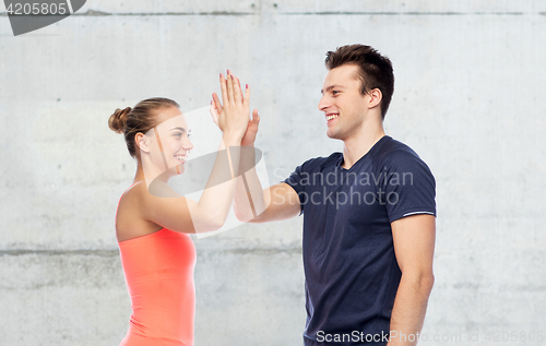 Image of happy sportive man and woman making high five