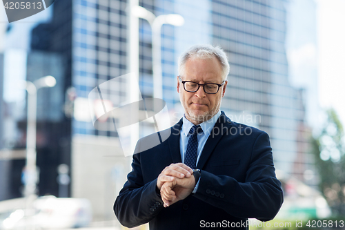 Image of senior businessman checking time on his wristwatch
