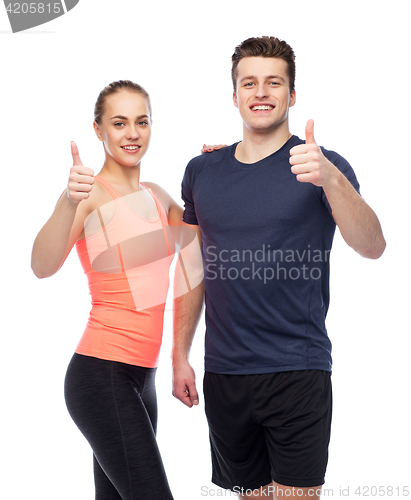 Image of happy sportive man and woman showing thumbs up