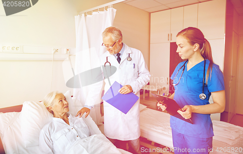 Image of doctor and nurse visiting senior woman at hospital