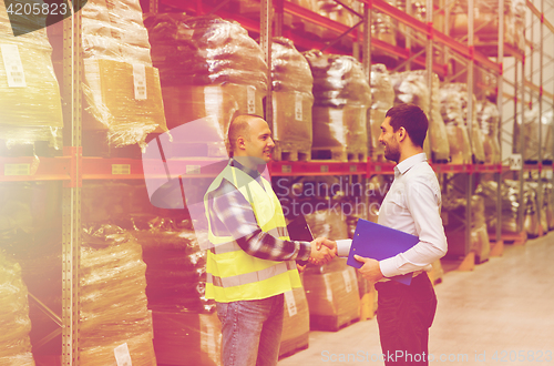 Image of worker and businessmen with clipboard at warehouse