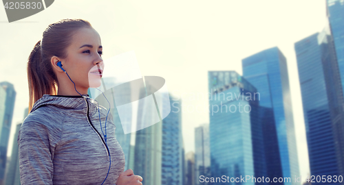 Image of happy woman with earphones running in city