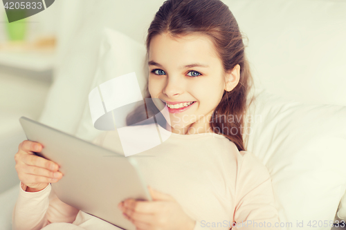 Image of happy girl lying in bed with tablet pc at home