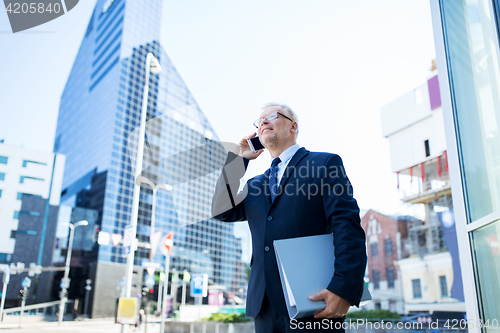 Image of senior businessman calling on smartphone in city