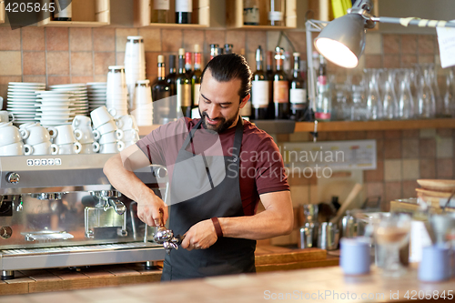 Image of barista with holder and tamper making at coffee