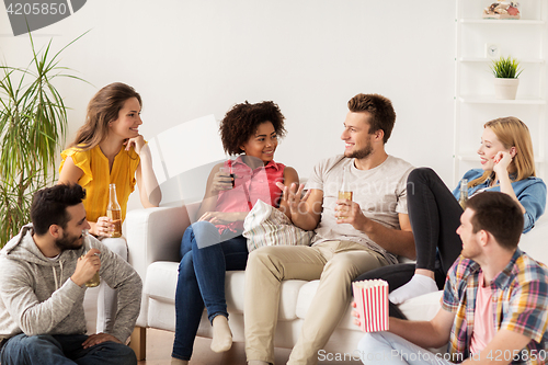 Image of happy friends with popcorn and beer at home
