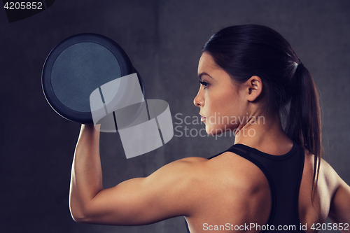 Image of young woman flexing muscles with dumbbells in gym