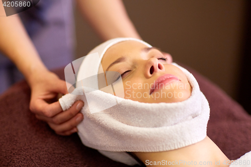 Image of woman having face massage with towel at spa