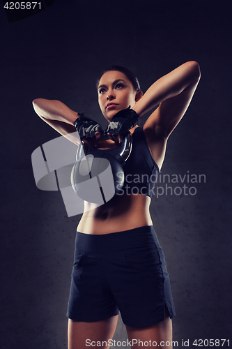 Image of young woman flexing muscles with kettlebell in gym